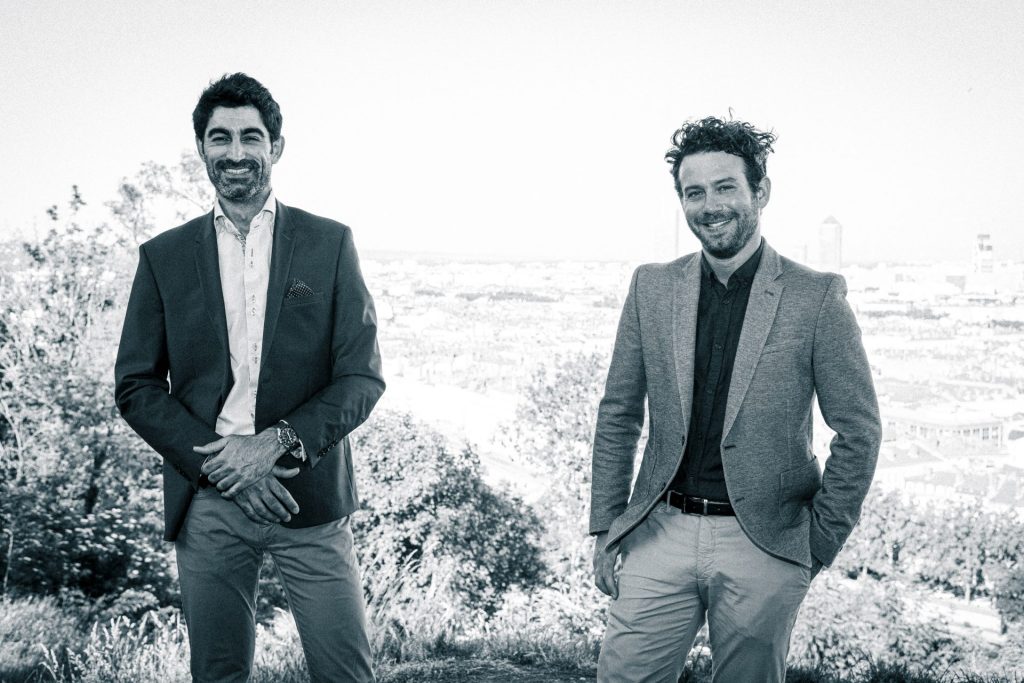 Les deux associés d'Hospitali-t Hadrien Bobillon et Adrien Guillaume debout devant un paysage