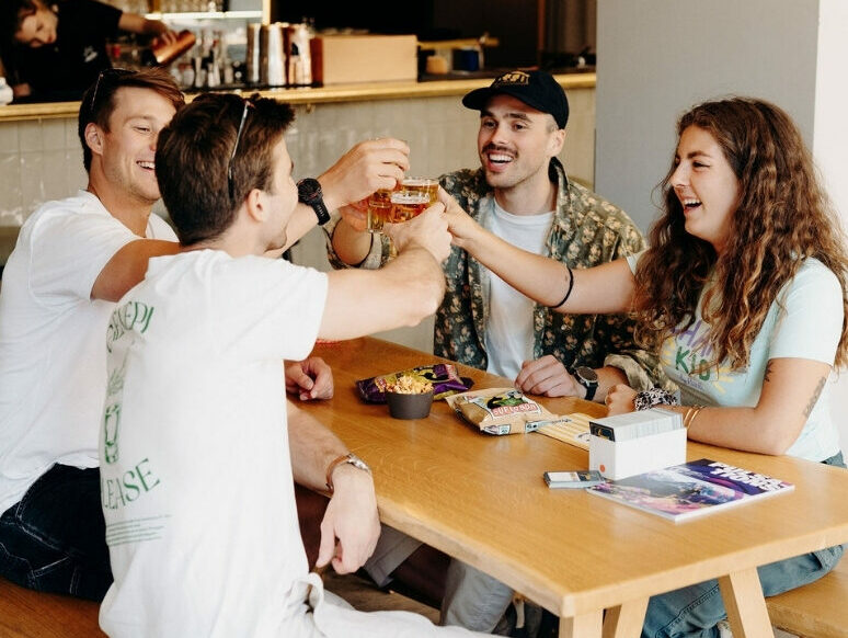 4 amis qui trinquent autour d'une table dans l'hôtel